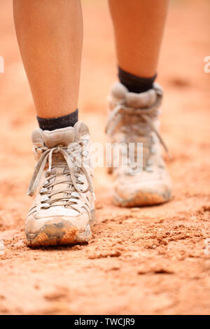 Scarpe da trekking - close up di sporco escursionista scarpe. Piedi di donna femmina e gli escursionisti calzature calzatura camminando sul sentiero sterrato escursione il percorso outdoor in natura. Foto Stock