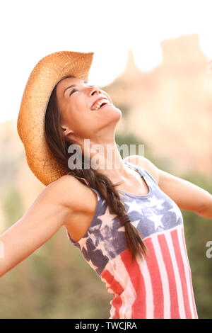 American cowgirl donna libera e felice di indossare il cappello da cowboy in esterno e in campagna. Allegro euforico gioiosa donna sorridente godendo della libertà. Bellissima gara di misto caucasico asiatici modello femminile. Foto Stock