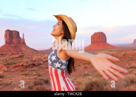 Cowgirl - donna felice e libera nella Monument Valley che indossa il cappello da cowboy con le braccia aperte nel concetto di libertà. Bella sorridente multirazziale giovane donna all'aperto, Arizona Utah, Stati Uniti d'America. Foto Stock