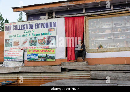 Negoziante seduta all'ingresso del suo negozio su dal lago, Srinagar, Jammu e Kashmir India Foto Stock