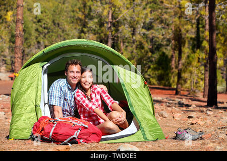 Persone in Campeggio in tenda - happy backpacking giovane nella foresta. Camper sorridendo felice all'aperto nella foresta. Felice multirazziale giovane avendo divertimento rilassante in attività all'aperto. Donna asiatica, uomo caucasico Foto Stock