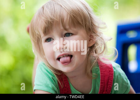 Piccolo bambino ragazza caucasica faccia closeup sul verde estate sfondo all'aperto Foto Stock