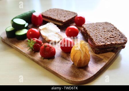 Chiudere la vista su una sana colazione tedesca con panini Pomodori Cetrioli e fragole Foto Stock