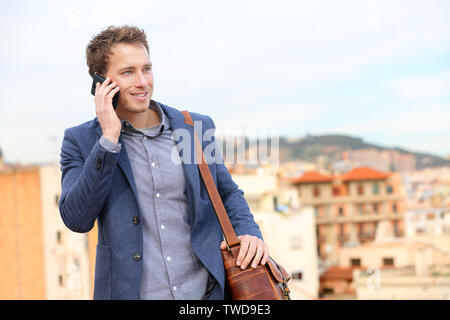 L'uomo sullo smartphone - il giovane uomo d affari parlando al telefono intelligente. Casual urbano imprenditore professionale tramite telefono cellulare sorridendo felice a piedi. Uomo bello indossare giacca tuta in Barcellona, Spagna Foto Stock