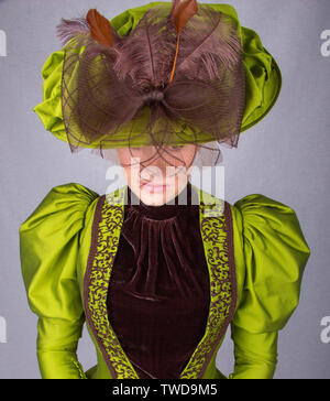 Late Victorian donna che indossa una seta verde ensemble e un cappello di grandi dimensioni Foto Stock