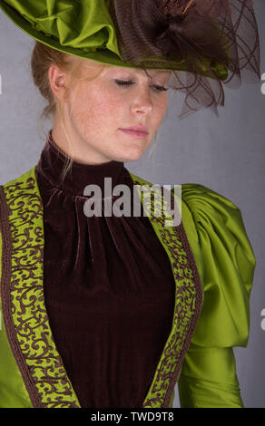 Late Victorian donna che indossa una seta verde ensemble e un cappello di grandi dimensioni Foto Stock