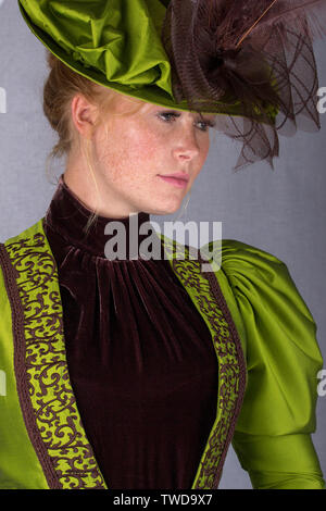 Late Victorian donna che indossa una seta verde ensemble e un cappello di grandi dimensioni Foto Stock