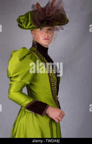 Late Victorian donna che indossa una seta verde ensemble e un cappello di grandi dimensioni Foto Stock