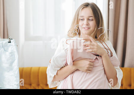 Abbigliamento, moda, stile e concetto di persone - donna scegliendo i vestiti a casa guardaroba. Malinconici bella giovane donna desiding cosa indossare in mor Foto Stock