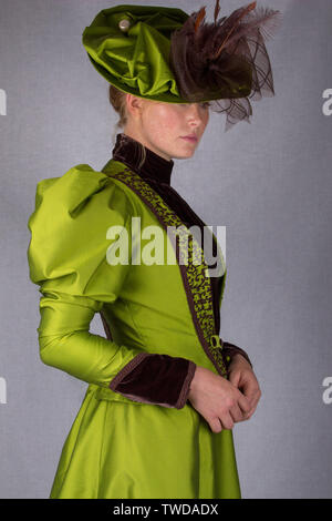 Late Victorian donna che indossa una seta verde ensemble e un cappello di grandi dimensioni Foto Stock