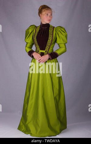 Late Victorian donna che indossa una seta verde ensemble e un cappello di grandi dimensioni Foto Stock