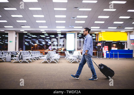 Uomo asiatico traveler con le valigie a piedi ed il trasporto di un aeroporto Foto Stock