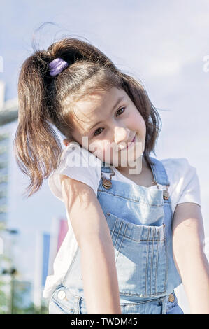 Carino felice ragazza caucasica in tuta in jeans sorridente. Stile di vita Foto Stock