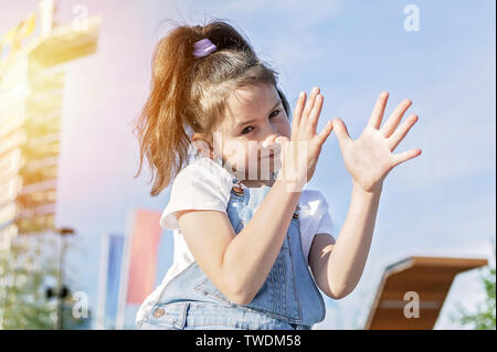 Carino felice ragazza caucasica in tuta in jeans smorfie sul cielo dello sfondo. Allegro emozione. Stile di vita Foto Stock