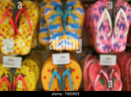 Immagine sfocata della fila di colori vivaci sandali da spiaggia appeso sul rack Foto Stock