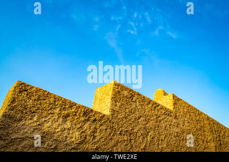 Il giallo muro di pietra in forme geometriche sul cielo blu sullo sfondo. Da Muscat Oman. Foto Stock