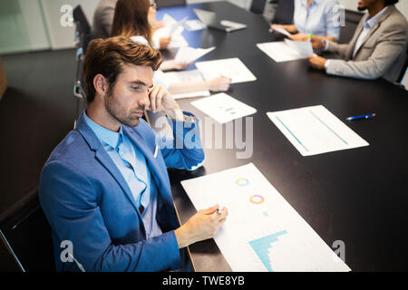 Gruppo di tentativi di persone di affari e mal gestite azienda porta infelicità Foto Stock