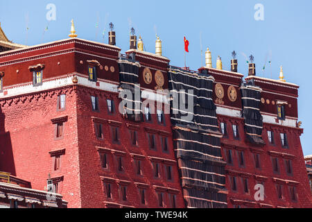 Ingrandendo la parte centrale del palazzo del Potala: Rosso un muro di mattoni, ornamenti dorati, la bandiera cinese sventola sulla cima dell'edificio. Patrimonio Mondiale dell'Unesco. Foto Stock
