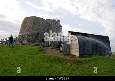 Una fila di vecchie barche da pesca ora utilizzate come capannoni di stoccaggio generale vicino al Castello di Lindisfarne, una piccola fortezza costruita nel 1550 sull'Isola Santa di Lindisfarne Foto Stock