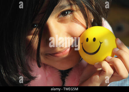 Ritratto di una ragazza che tiene una palla con faccia sorridente Foto Stock