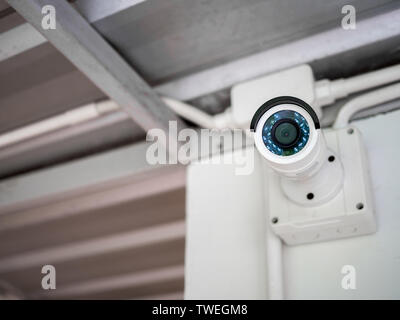 Close-up white telecamera TVCC sulla parete sotto il tetto. Moderna sicurezza CCTV fotocamera con copia spazio. Foto Stock