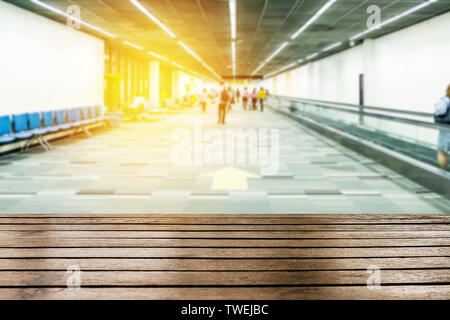 Tavola in legno sulla parte superiore sfumata i passeggeri a piedi porta in aeroporto Foto Stock