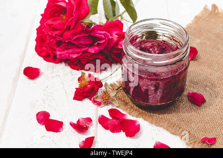 Confettura di petali di rosa in un vaso di vetro su uno sfondo luminoso. Confettura di fiori. Cibo sano. Spazio di copia Foto Stock