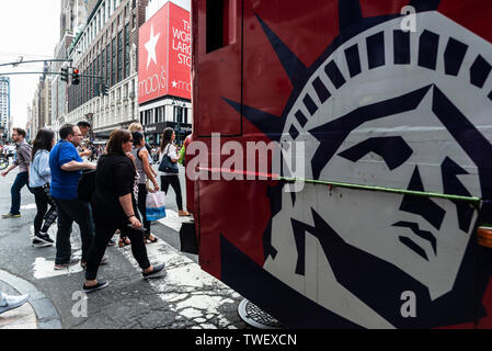 La città di New York, Stati Uniti d'America - 31 Luglio 2018: Persone che attraverso un passaggio pedonale di fronte Macys con un disegno della Statua della Libertà su un bus in M Foto Stock