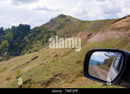 La riflessione di una strada di montagna in un specchio auto in Georgia Foto Stock