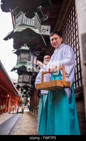 Angolo basso ritratto di monaci accensione lanterne al di Kasuga Taisha Sacrario di Nara in Giappone. Foto Stock