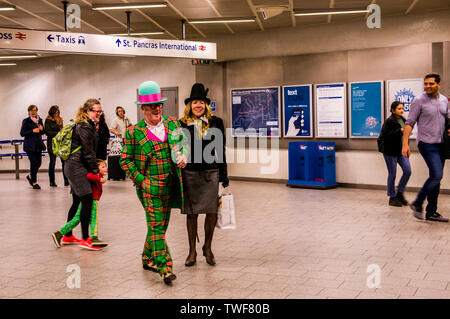 Giovane vestito in abiti stravaganti camminando attraverso la stazione metropolitana di Kings Cross a Londra. Foto Stock