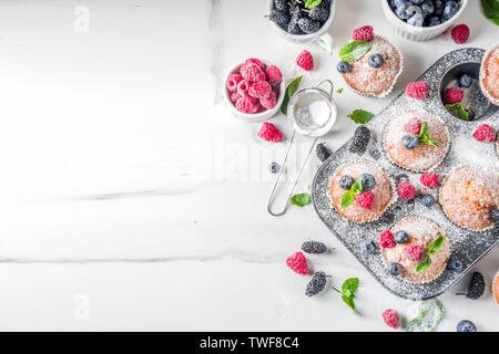 In casa la vaniglia muffin o tortine con frutti di bosco freschi su marmo bianco sullo sfondo Foto Stock