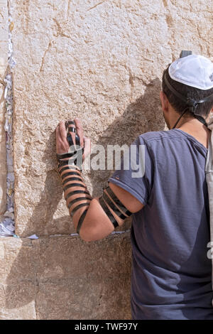 Un giovane uomo che indossa un zucchetto phylacteries e prega con fervore presso il Muro occidentale nella città vecchia di Gerusalemme, Israele. Foto Stock