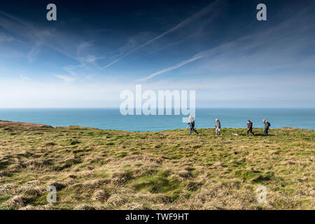 Un gruppo di escursionisti maturi e un cane a camminare lungo la costa sud occidentale il percorso sul North Cornwall coast. Foto Stock