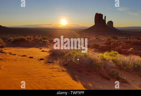 Il Monument Valley Navajo Tribal Park nel confine Arizona-Utah USA, a sunrise. Il sorgere del sole dietro le rocce rosse, cielo chiaro sfondo Foto Stock