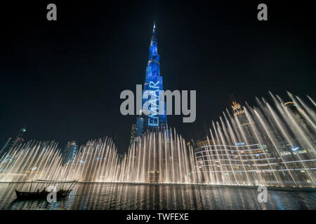 La fontana di Dubai danze sotto la illuminata Burj Khalifa come passeggeri su una barca guarda. Foto Stock