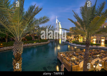 Il bellissimo lungomare di Souk Madinat Jumeirah e l'hotel di 7 stelle Burj al Arab sono incorniciate da eleganti palme a Dubai. Foto Stock