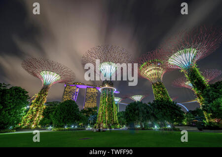 Nuvole whisp sulla drammatica supertrees di Singapore con la mitica Marina Bay Sands in background. Foto Stock