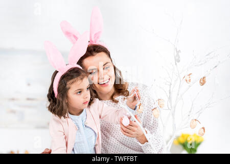 Beata madre e figlia nelle orecchie di coniglietto decorazione albero di pasqua Foto Stock