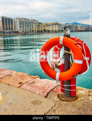 Salvagenti anulari su Wharf a Salonicco e Nikis Avenue in background. La Grecia Foto Stock