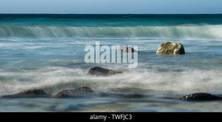 Una lunga esposizione moto onde sfocata e mare e rocce Uttakleiv Beach, Isole Lofoten , Norvegia Foto Stock