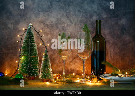 Vino rosso sul tavolo con albero di Natale. Tavolo da pranzo e luci di Natale. Foto Stock