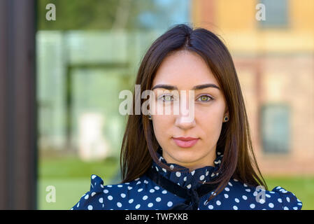 Close up di un grave criptica elegante giovane donna in un elegante blu e bianco vestito e spazio di copia Foto Stock