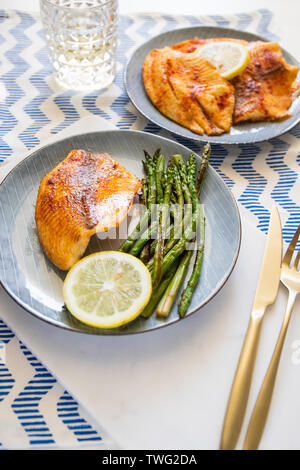 Cotta di pesci di Tilapia con asparagi su una piastra di ceramica. Una sana dieta mediterranea il pranzo o la cena. Foto Stock