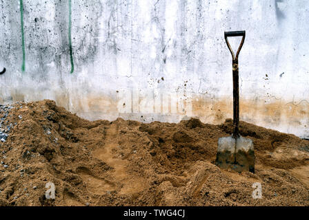 Le pale che sono collocati sulla sabbia della pila sono utilizzati per la protezione della sabbia nel contenitore per essere miscelato con il cemento nella costruzione. Foto Stock