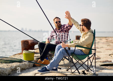 Happy amici con canne da pesca sul molo Foto Stock