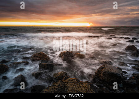 Tempesta sulla riva: mare mosso lungo il litorale di Whitehead all'alba. Foto Stock