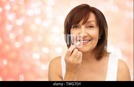 Sorridente donna senior il rossetto per labbra Foto Stock