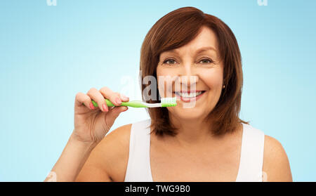 Senior donna con spazzolino da denti spazzolare i suoi denti Foto Stock