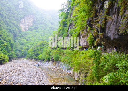 Magnifica Taroko Gorge nel Parco Nazionale di Taroko, Taiwan catturato con turisti escursionismo in un giorno di pioggia con nebbia in background. Verde foresta tropicale, nebbia. Natura e paesaggio. Foto Stock